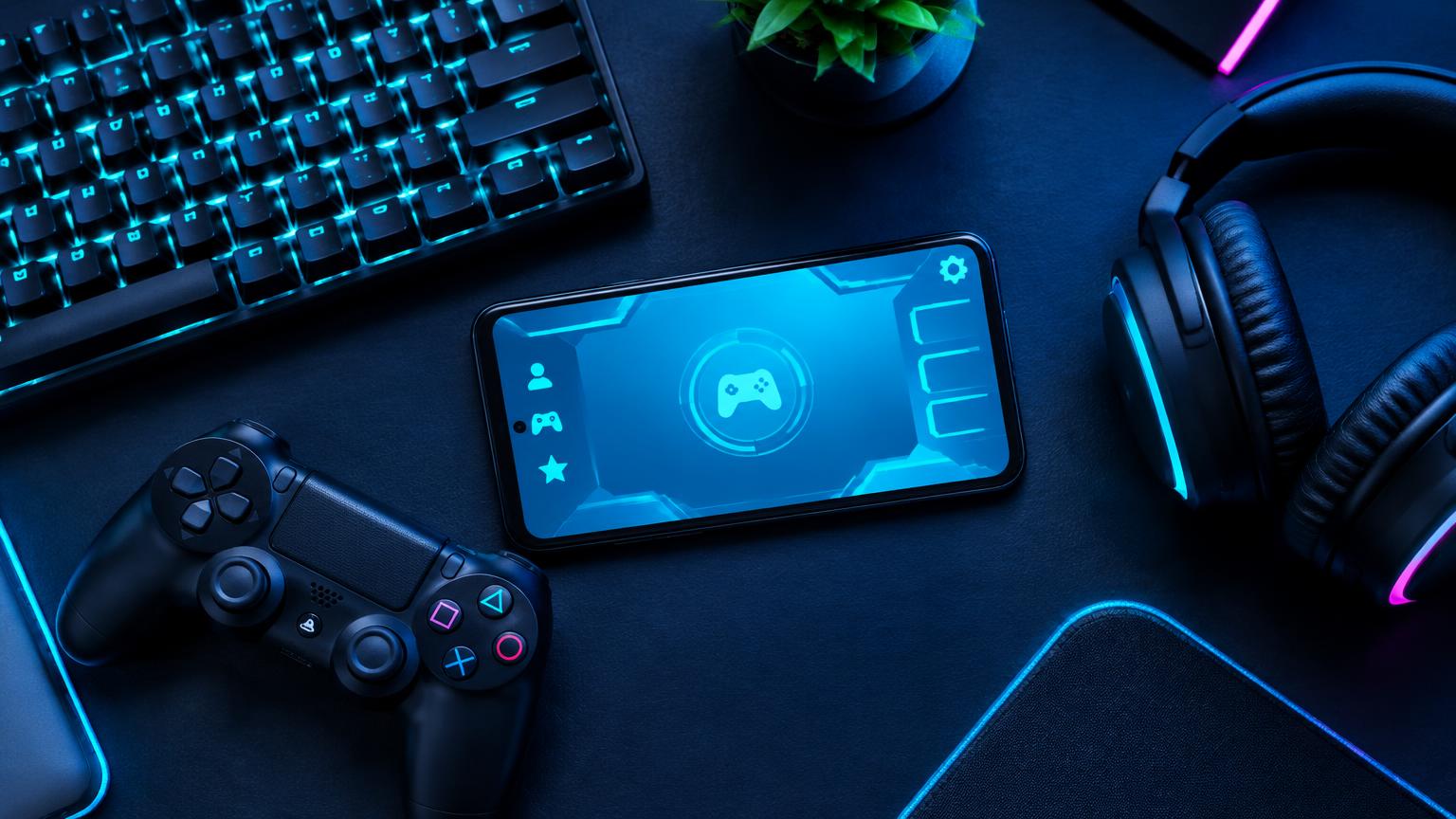 Gaming phone, controller and keyboard on a blue-lit desk